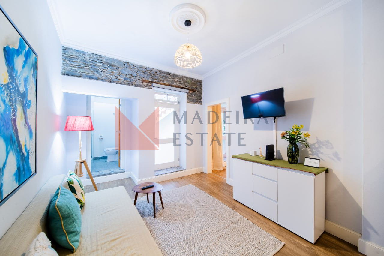 Sala de estar com televisão, cómoda, sofá e mesa de café num apartamento de aluguer de curta duração no Funchal