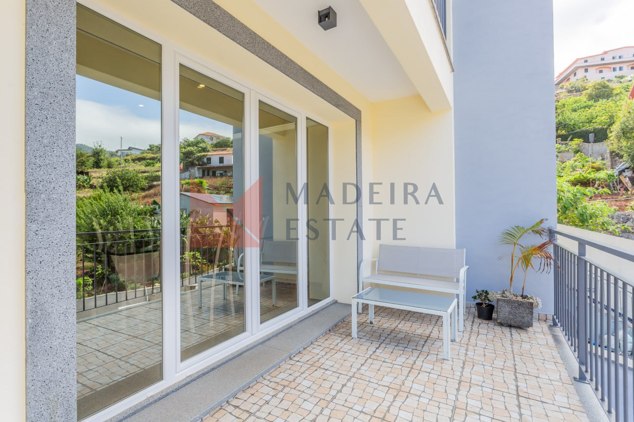 Panoramic windows offering stunning views of the mountains and city at Machico Oasis vacation home in Madeira