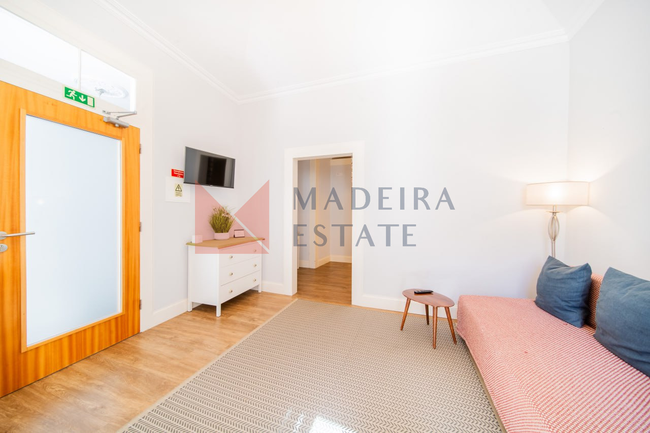 Sala de estar acolhedora com sofá, mesa de café, cómoda e televisão num apartamento de aluguer de curta duração no Funchal