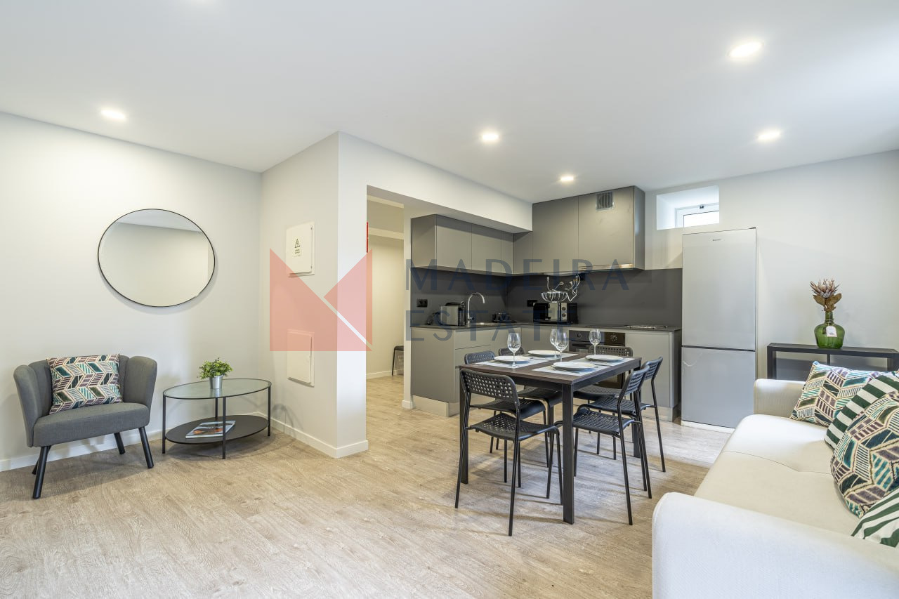 Open-plan kitchen with living room featuring sofa, armchair, coffee table, and mirror at JMF House, São Vicente, Madeira