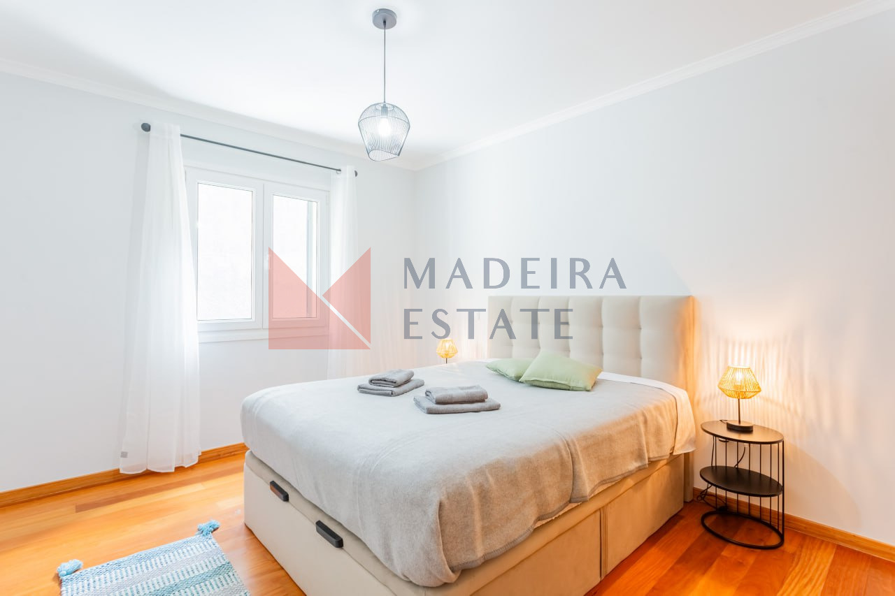 Bright bedroom with double bed and bedside table in vacation rental home in Madeira