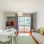 Bright living room with parquet floor, sofa, dining table, TV, and balcony access – JMF Apartment, Madeira short-term rental